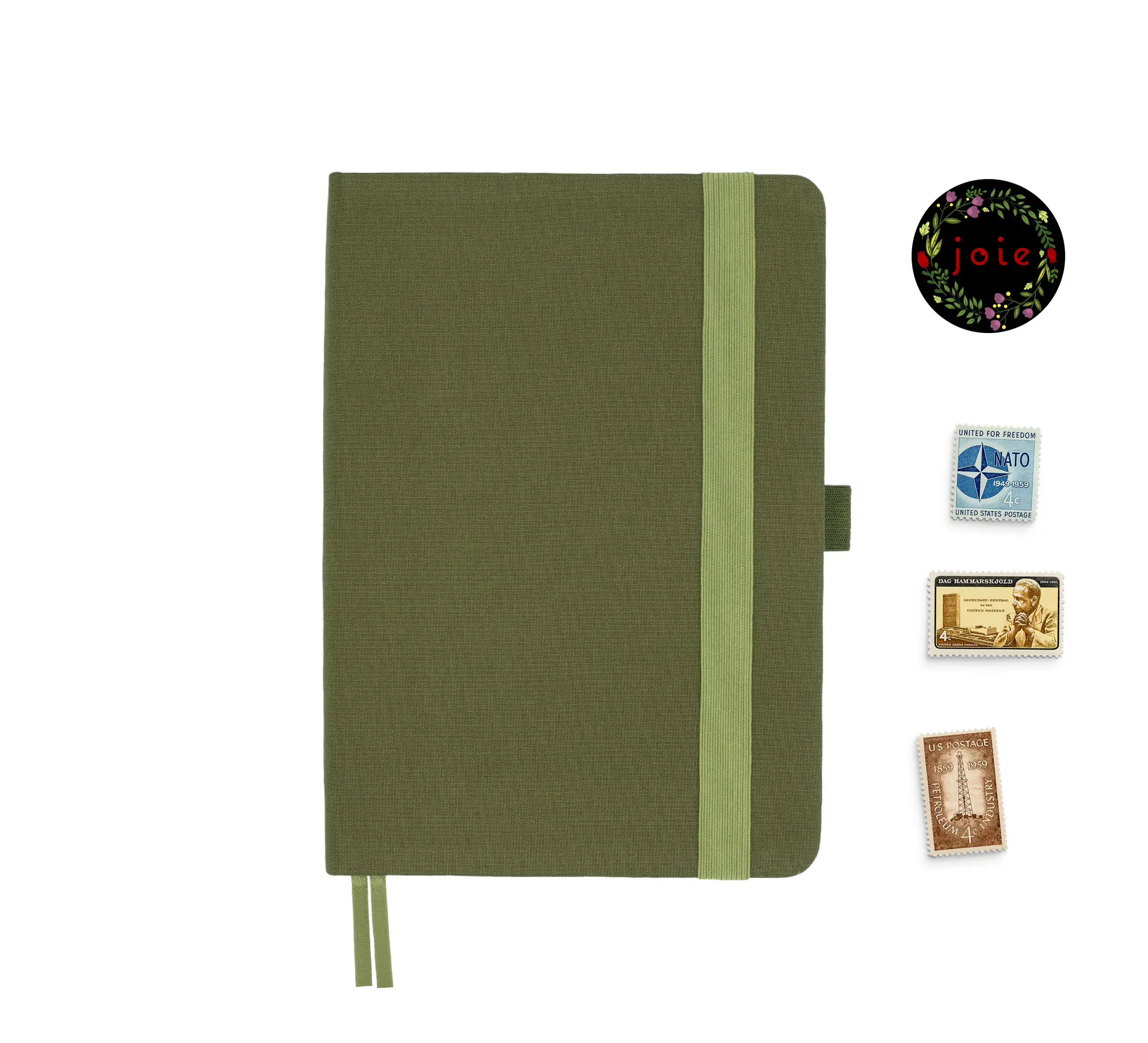 Olive green fabric-covered notebook with rounded corners, matching elastic band, pen loop, and dual ribbon bookmarks, displayed alongside three vintage postage stamps and a floral 'joie' logo