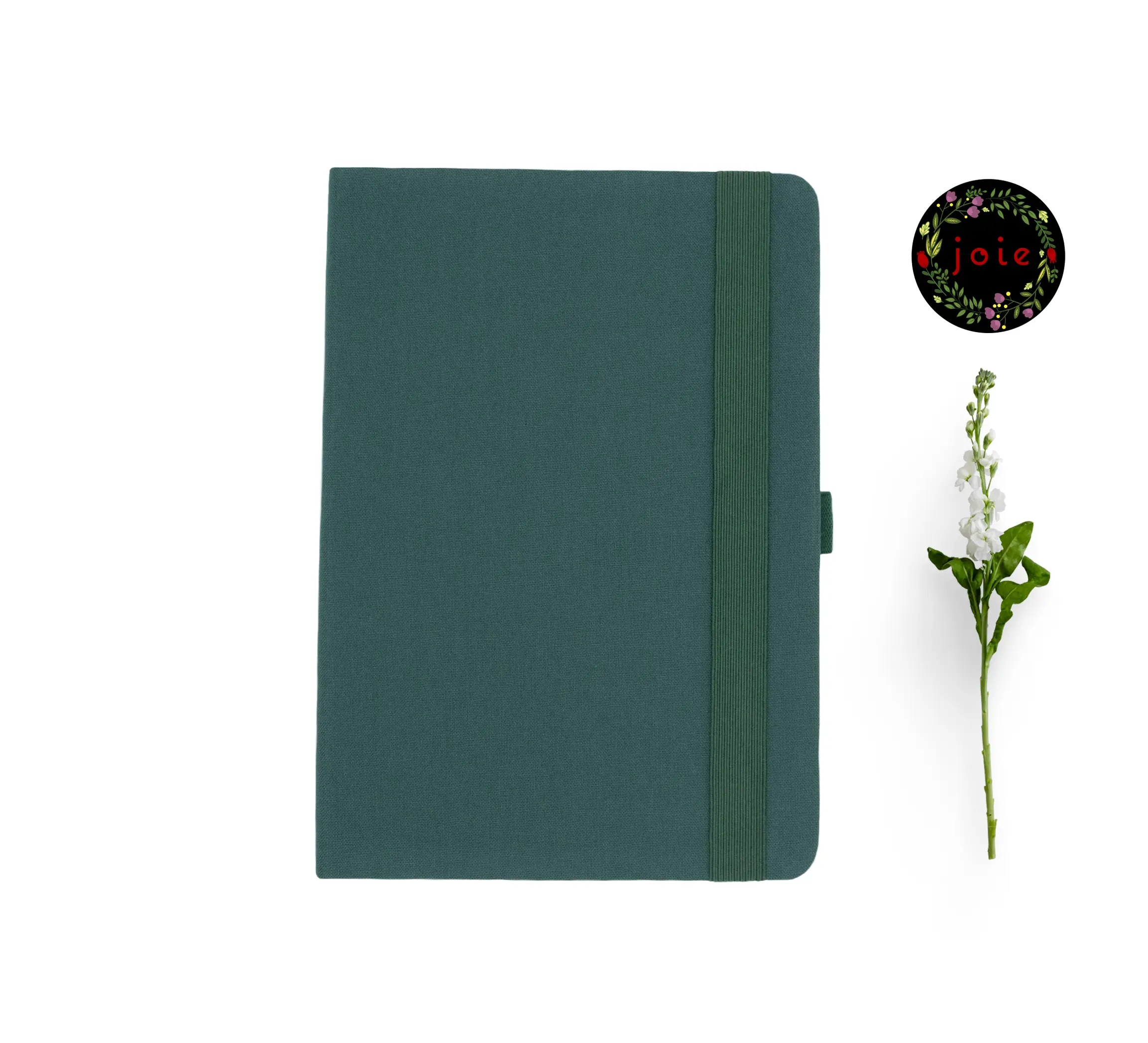 Deep green fabric-covered notebook with rounded corners, matching elastic band, pen loop, and dual ribbon bookmarks, shown with a white flower and a floral 'joie' logo